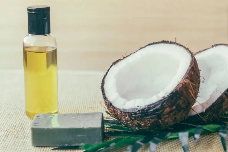 Coconut oil bottle, and a half-coconut on a textured surface