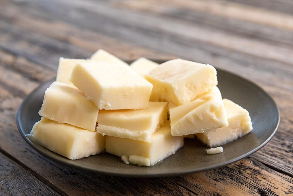 Cubes of white tallow on a dark plate with a wooden background