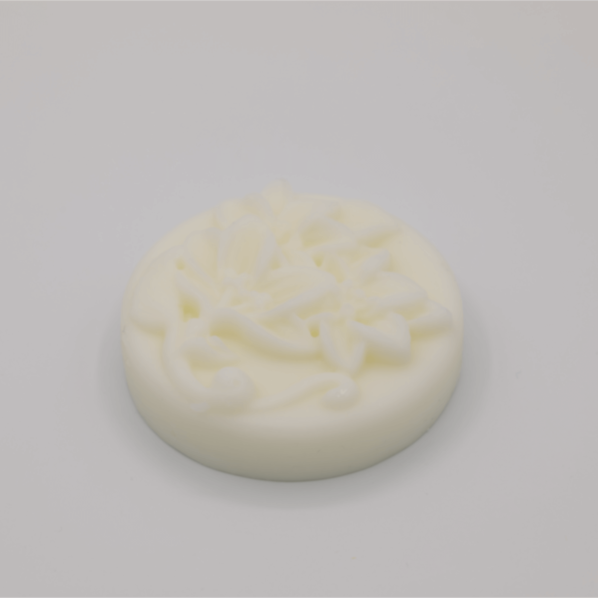 Round white tallow bar with floral decorations on a gray background