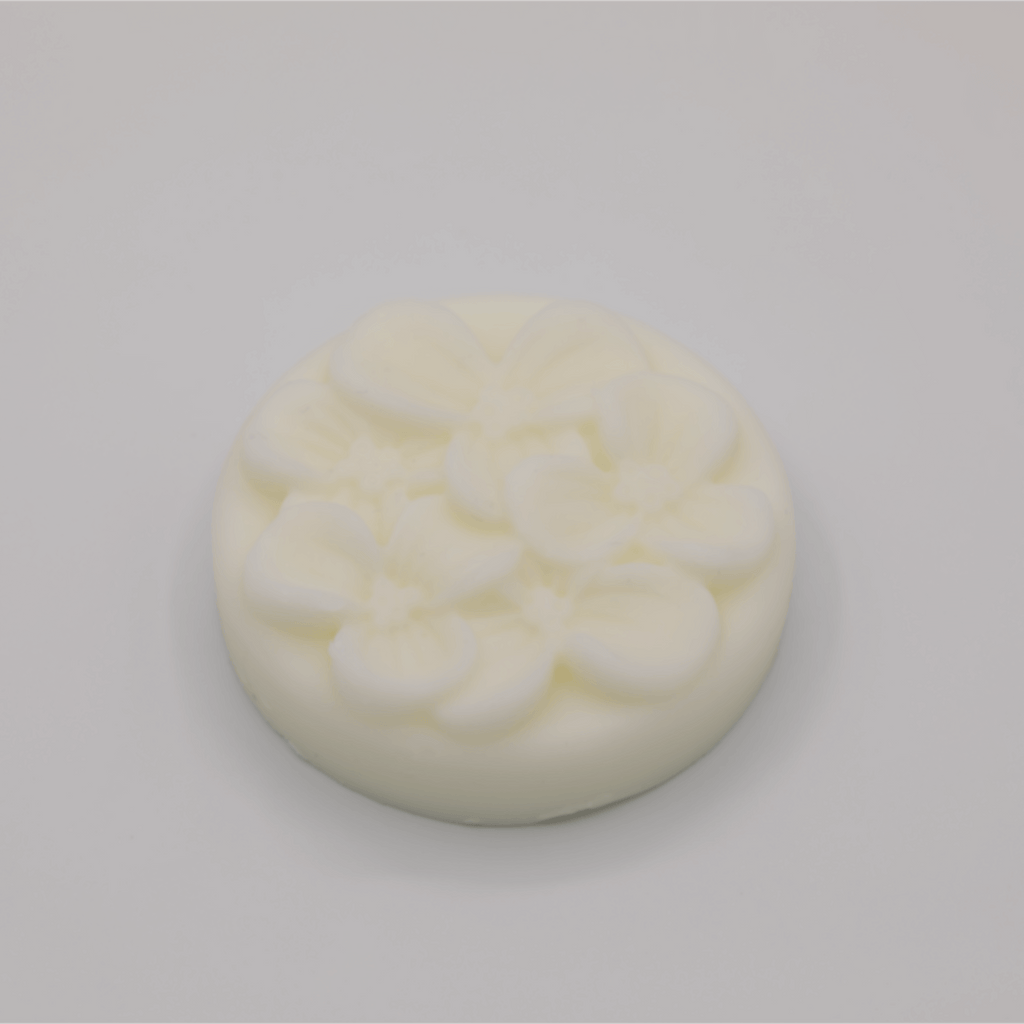 Round white tallow bar with a floral surface on a light gray background