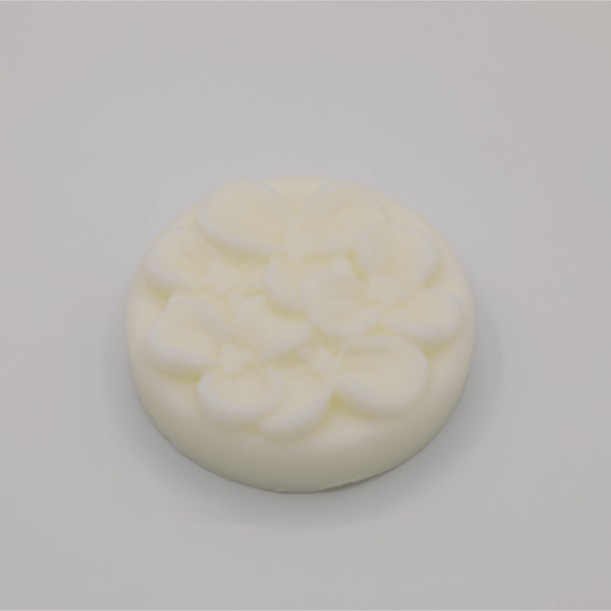 Round white tallow bar with a floral surface on a light gray background