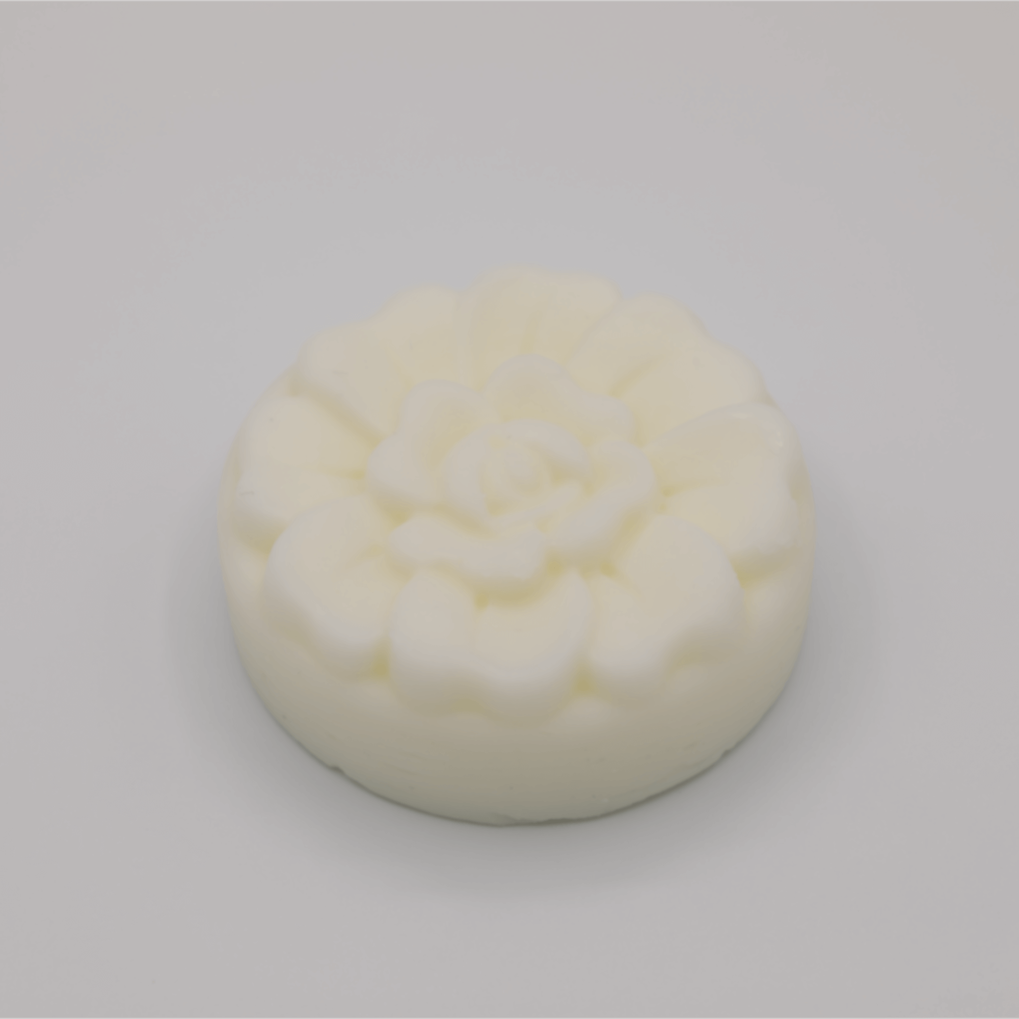 Round white tallow bar with floral pattern on a gray background