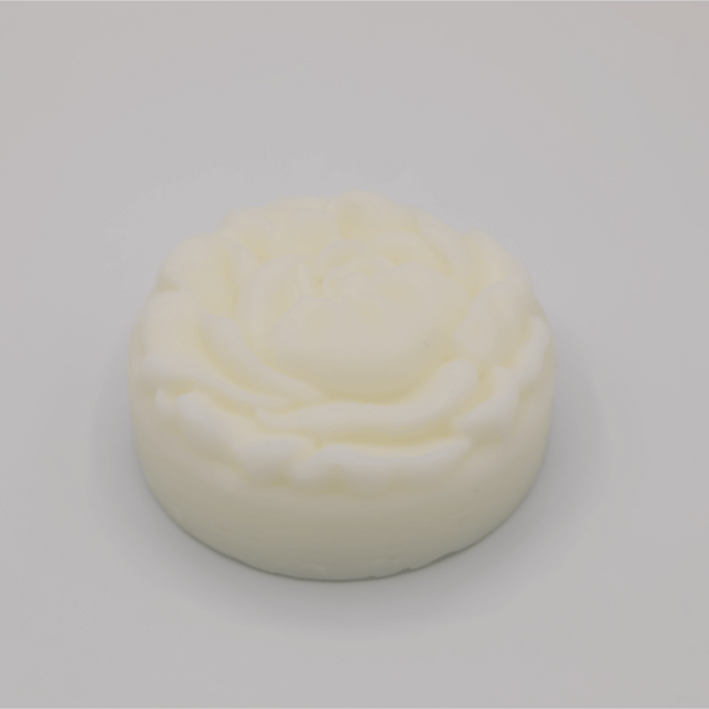 Round, white tallow bar with a floral pattern on a light gray background