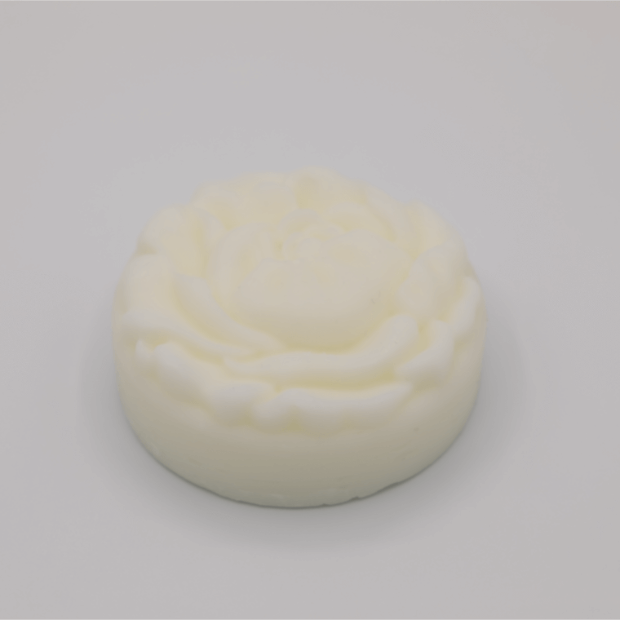 Round, white tallow bar with a floral pattern on a light gray background