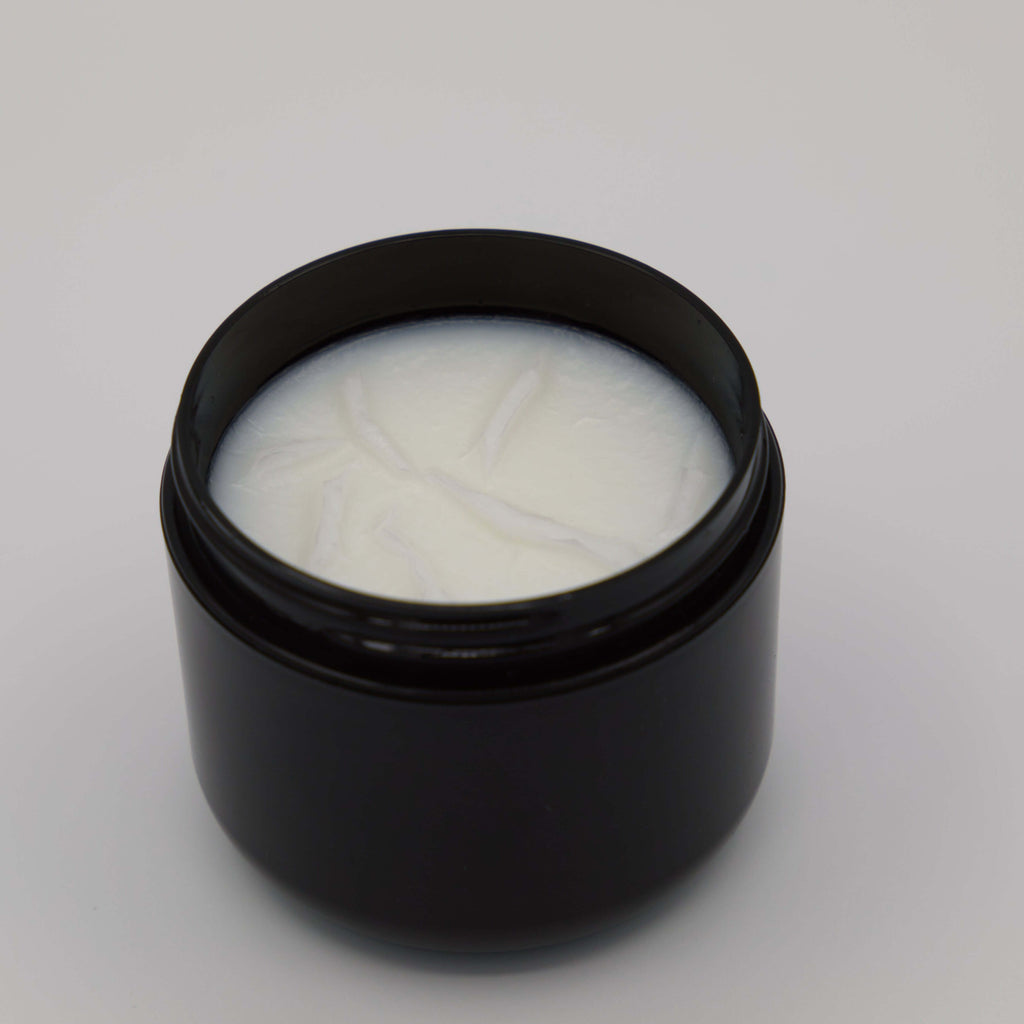 Black jar with a white tallow cream on a light gray background