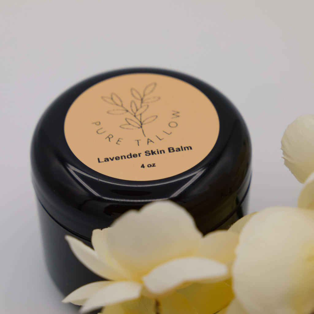 Black jar of Pure Tallow Lavender Skin Balm with flowers in the foreground