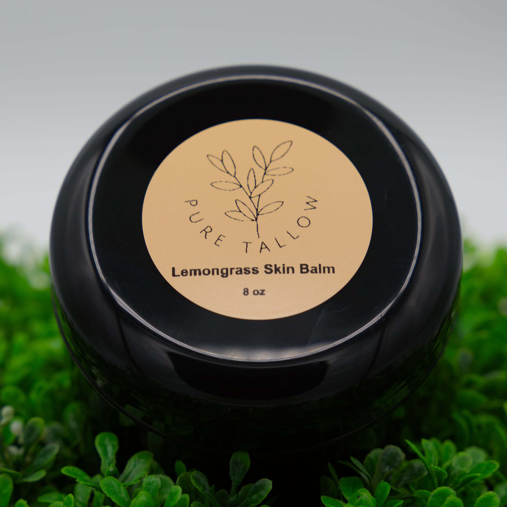Black jar of Pure Tallow Lemongrass Skin Balm on a grass background